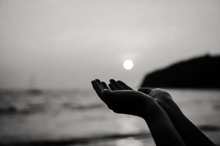 Woman hands place together like praying in front of nature green bokeh and blue sky  background.の写真素材