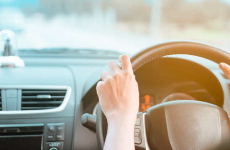 Hand of woman on steering wheel drive a car with sunlight background.の写真素材