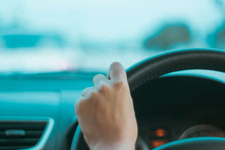 Hand of woman on steering wheel drive a car with sunlight background.の写真素材
