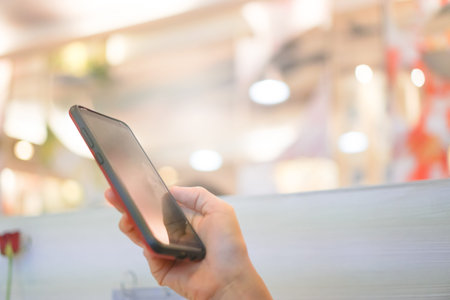 Woman hand using smartphone in mall with colorful bokeh light background.の写真素材