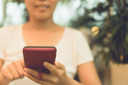 Woman hand using smartphone or tablet to do business, financial social network  with coffee cafe nature backgroundの写真素材