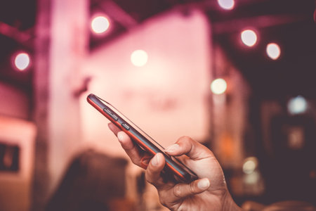 Woman hand using smartphone with cafe shop colorful highlight shade to object beautiful background.