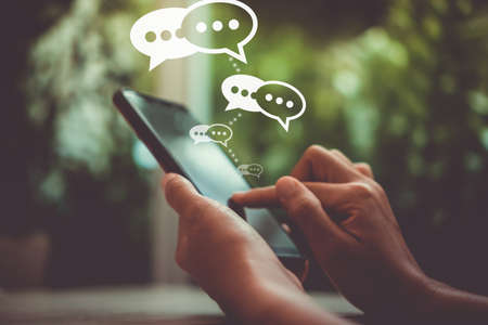 Women hand using smartphone typing, chatting conversation in chat box icons pop up.の写真素材