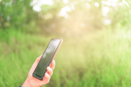 Copy space lady hand using smartphone with green nature abstract background.の写真素材