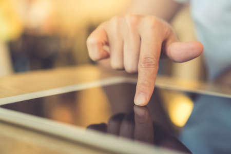 Woman's hand using big tablet to do work, planning, reading in coffee cafe with bokeh light background.の写真素材
