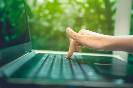 Woman's hand using laptop to work study with cafe shop colorful highlight shade to object beautiful...