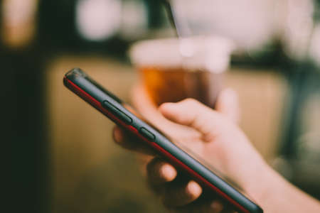 Woman hand using smartphone and laptop with cafe shop colorful highlight shade to object beautiful background. Business, financial, trade stock maket and social network concept.の写真素材