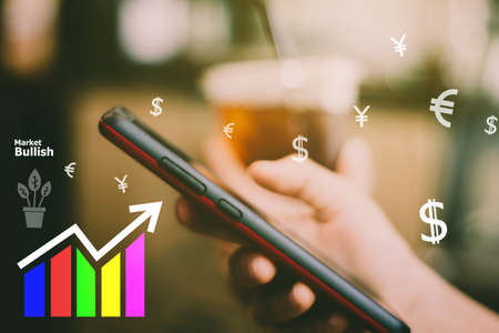 Fintech various currencies sign icon and market stock graph screen of smartphone with colorful bokeh blur background. Financial business technology freedom dream life using internet concept.の写真素材