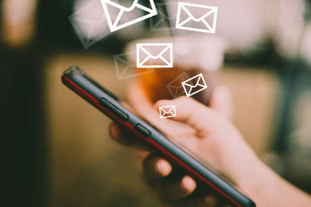 Woman hand using smartphone to send and recieve email for business on bokeh vintage color tone background.の写真素材