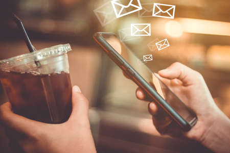 Woman hand using smartphone to send and recieve email for business on bokeh vintage color tone background.の写真素材