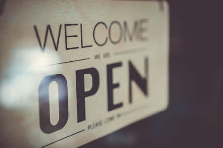 A business sign that says âOpenâ on cafe or restaurant hang on door at entrance. Vintage color tone style.の写真素材