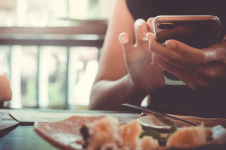 Woman hand using laptop and smartphone to work study with cafe shop colorful highlight shade to object beautiful background. Business, financial, trade stock maket and social network concept.の写真素材