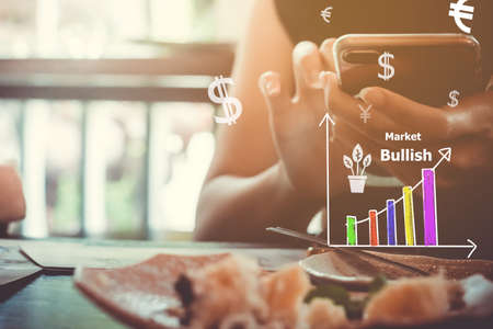 Fintech various currencies sign icon and market stock graph screen of smartphone with colorful bokeh blur background. Financial business technology freedom dream life using internet concept.の写真素材