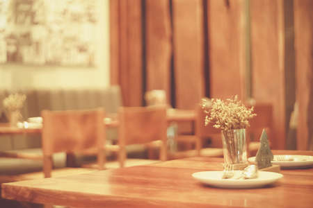 Blur table setup plate  and flower for customer in restutant cafe background vintage tone color style.の写真素材