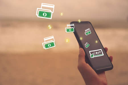 Women hand using smartphone do online shopping screen with many icons 
 such as  buy icon, dollar symbol and bank note. Social media maketing  concept.の写真素材