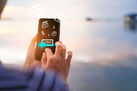 Women hand using smartphone do online shopping screen with many icons 
 such as  buy icon, dollar symbol and bank note. Social media maketing  concept.の写真素材
