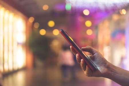 Woman hand using smartphone beautiful bokeh background. Business, financial, trade stock maket and social network concept.の写真素材