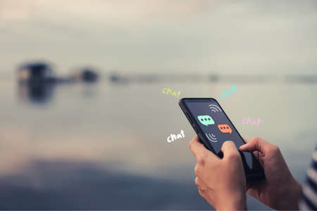 Women hand using smartphone typing, chatting conversation in chat box icons pop up. Social media maketing technology concept.Vintage soft color tone background.の写真素材