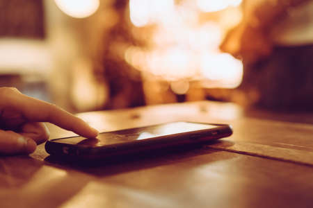 Woman hand using smartphone and laptop with cafe shop colorful beautiful bokeh background. Business, financial, trade stock maket and social network concept.の写真素材