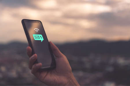 Woman hand using smartphone and it's show 1 email recieve notification icon pop up on screen of mobile phone. Business communication  technology concept.の写真素材