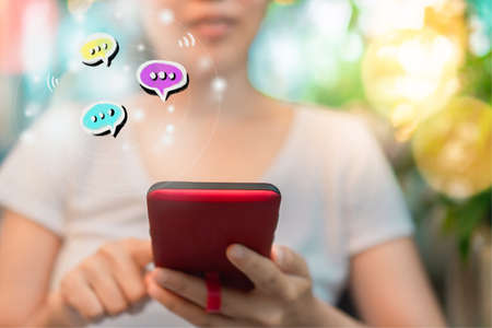 Women hand using smartphone typing, chatting conversation in chat box icons pop up. Social media maketing technology concept.Vintage soft color tone background.の写真素材