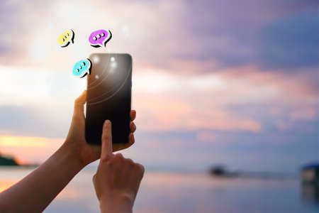 Women hand using smartphone typing, chatting conversation in chat box icons pop up. Social media maketing technology concept.Vintage soft color tone background.の写真素材