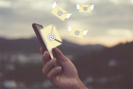 Woman hand using smartphone to send and recieve email for business on bokeh vintage color tone background.の写真素材