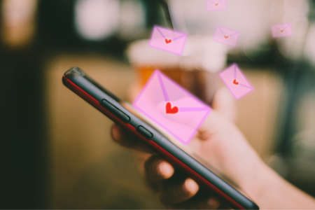 Woman hand using smartphone to send and recieve email love letter.の写真素材