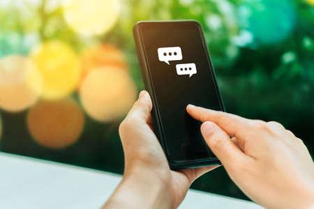 Women hand using smartphone typing, chatting conversation in chat box icons pop up. Social media maketing technology concept.Vintage soft color tone background.の写真素材
