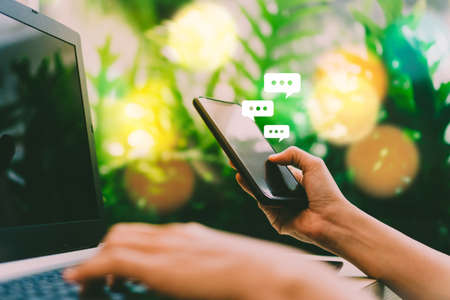 Women hand using smartphone typing, chatting conversation in chat box icons pop up. Social media maketing technology concept.Vintage soft color tone background.の写真素材