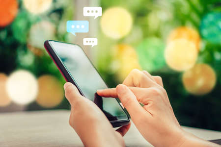 Women hand using smartphone typing, chatting conversation in chat box icons pop up. Social media maketing technology concept.Vintage soft color tone background.の写真素材