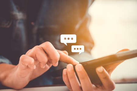 Women hand using smartphone typing, chatting conversation in chat box icons pop up. Social media maketing technology concept.Vintage soft color tone background.の写真素材