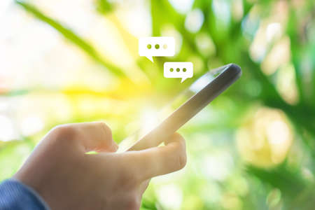 Women hand using smartphone typing, chatting conversation in chat box icons pop up. Social media maketing technology concept.Vintage soft color tone background.の写真素材