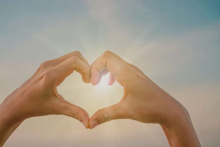 Woman hand do heart shape on nature blue sky background.の写真素材