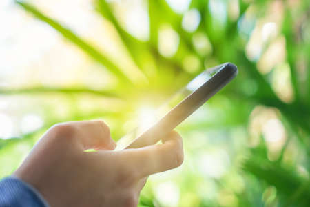 Woman hand using smartphone with cafe shop colorful beautiful bokeh background. Business, financial, trade stock maket and social network concept.の写真素材