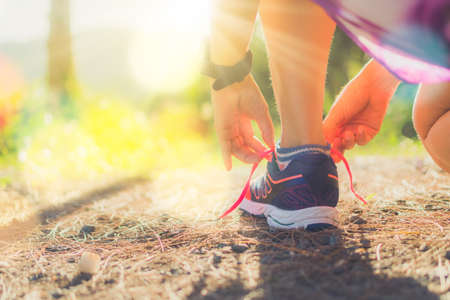 Woman wear running shoe on to walking and running on nature green background.Health exercise concept.の写真素材