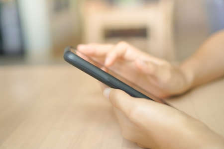 Woman hand using smartphone with cafe shop colorful beautiful bokeh background. Business, financial, trade stock maket and social network concept.の写真素材