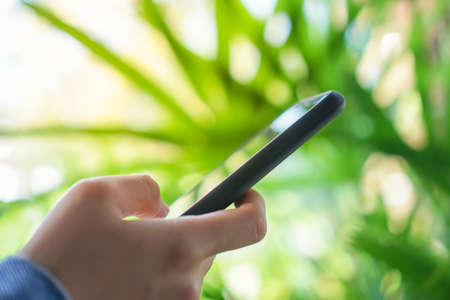Woman hand using smartphone with cafe shop colorful beautiful bokeh background. Business, financial, trade stock maket and social network concept.の写真素材
