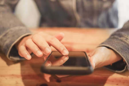Woman hand using smartphone and laptop with cafe shop colorful highlight shade to object beautiful background. Business, financial, trade stock maket and social network concept.の写真素材