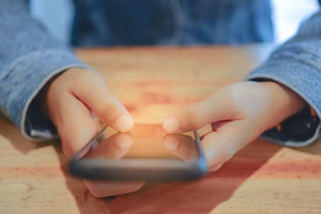 Woman hand using smartphone and laptop with cafe shop colorful highlight shade to object beautiful background. Business, financial, trade stock maket and social network concept.の写真素材