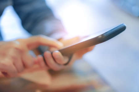 Woman hand using smartphone and laptop with cafe shop colorful highlight shade to object beautiful background. Business, financial, trade stock maket and social network concept.の写真素材