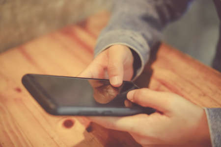 Woman hand using smartphone and laptop with cafe shop colorful highlight shade to object beautiful background. Business, financial, trade stock maket and social network concept.の写真素材