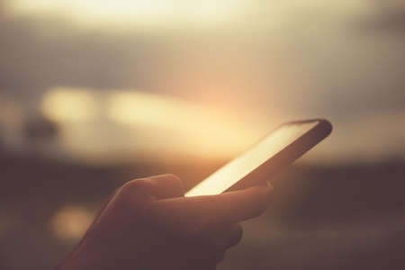 Woman hand using smartphone with nature green  beautiful background. Business, financial, trade stock maket and social network concept.の写真素材