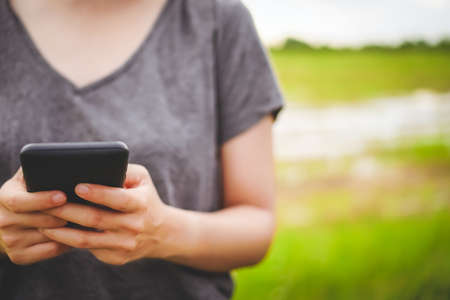 Woman hand using smartphone with nature green  beautiful background. Business, financial, trade stock maket and social network concept.の写真素材