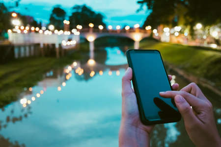 Woman is using smartphone in public park. Business, financial, trade stock maket and social network concept.の写真素材