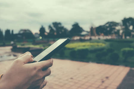 Woman is using smartphone in public park. Business, financial, trade stock maket and social network concept.の写真素材