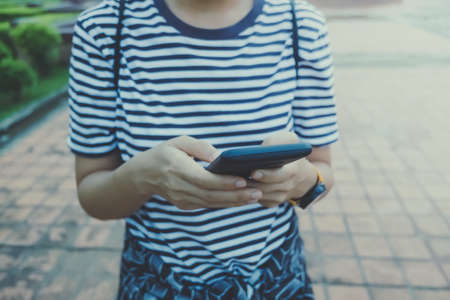 Woman is using smartphone in public park. Business, financial, trade stock maket and social network concept.の写真素材