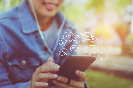 Women hand using smartphone typing, chatting conversation in chat box icons pop up. Social media maketing technology concept.Vintage soft color tone background.の写真素材