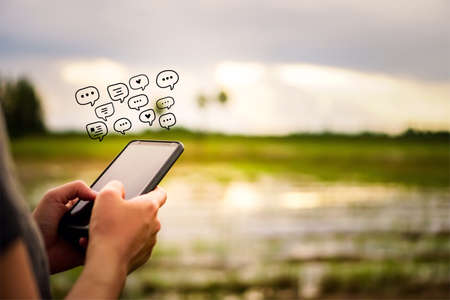 Women hand using smartphone typing, chatting conversation in chat box icons pop up. Social media maketing technology concept.Vintage soft color tone background.の写真素材