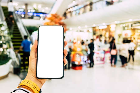 Woman hand using smartphone with shopping mall colorful beautiful bokeh copyspace white background. Business, financial, trade stock maket and social network concept.の写真素材